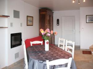 Holiday Home La Pailloussette - A في كانكال: طاولة غرفة الطعام مع إناء من الزهور عليها
