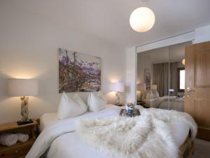 a bedroom with a large white bed with a large mirror at Apartment Chesa Ludains 8 by Interhome in St. Moritz
