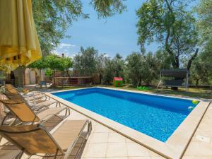 uma piscina com cadeiras e um guarda-sol em Holiday Home Duje & Mare - Mdn184 by Interhome em Ližnjan