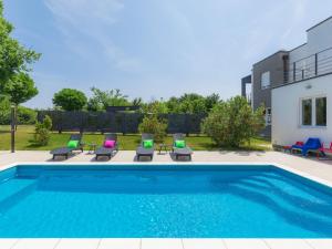 a swimming pool with chairs and a house at Holiday Home Mirna - MDN156 by Interhome in Ližnjan