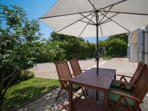 drewniany stół i krzesła z parasolem w obiekcie Holiday Home Graziani by Interhome w mieście Kornić