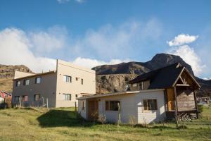 una casa vieja en un campo con montañas en el fondo en Posada y Cabañas El Barranco, en El Chaltén