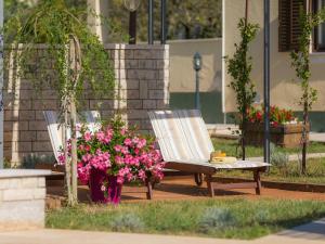 zwei Stühle und Blumen neben einem Gebäude in der Unterkunft Holiday Home Debora by Interhome in Vodnjan