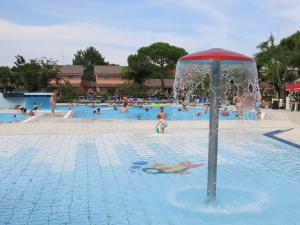 a pool with people playing in the water at Holiday Home Villaggio San Francesco 5-4 by Interhome in Duna Verde