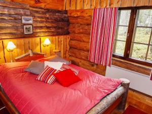 um quarto com uma cama vermelha num chalé de madeira em Holiday Home Örtsylä b by Interhome em Salla
