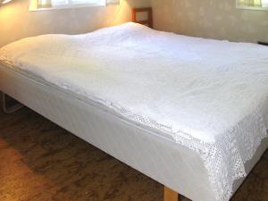 a large white bed in a room with two windows at Holiday Home Järnemåla Margaretetorp by Interhome in Valdemarsvik