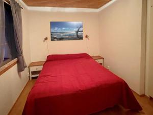 a bedroom with a red bed and a painting on the wall at Holiday Home Ylläsriekko - itätupa by Interhome in Ylläsjärvi