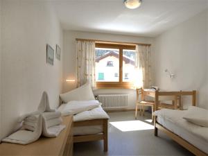 Zimmer mit 2 Betten, einem Tisch und einem Fenster in der Unterkunft Apartment Chesa Islas by Interhome in Pontresina
