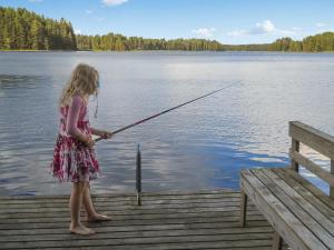 una niñita parada en un muelle sosteniendo una caña de pescar en Holiday Home Palkinniemi by Interhome, en Putikko