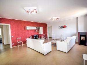 a living room with white chairs and a red wall at Villa Orange by Interhome in Solarino