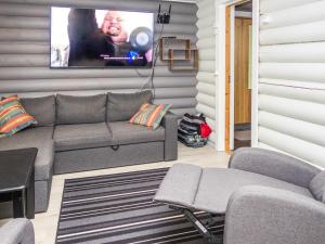 ein Wohnzimmer mit einem Sofa und einem Fernseher an der Wand in der Unterkunft Holiday Home Imponlampi by Interhome in Rukajärvi