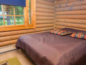 Bett in einem Blockhaus mit Fenster in der Unterkunft Holiday Home Imponlampi by Interhome in Rukajärvi