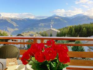 a vase of red roses on a table with mountains at Apartment Grand Large A-B-3 by Interhome in Crans-Montana
