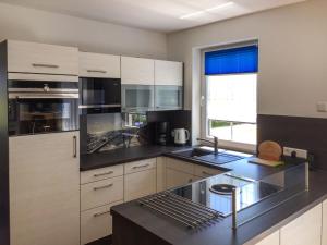 una cucina con armadi bianchi e piano di lavoro nero di Holiday Home Kleine Möwe by Interhome a Zirkow