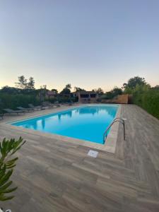 a large swimming pool with a wooden deck at Résidence Les Cigales in Porto-Vecchio