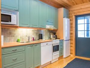 eine Küche mit grünen Schränken und einem weißen Kühlschrank in der Unterkunft Holiday Home Karhunpesä a by Interhome in Kotila + 14 Fotos