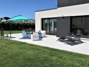 een patio met een groep stoelen en een parasol bij Holiday Home Villa Ty Coz by Interhome in Cléder