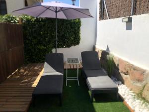 eine Terrasse mit 2 Stühlen und einem Tisch mit einem Sonnenschirm in der Unterkunft ESTUDIO MAESO in Manzanares el Real