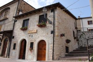 un antiguo edificio de piedra con macetas en las ventanas en B&B Casa Antonetti en Campo di Giove