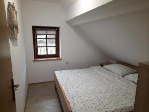a white bedroom with a bed and a window at Vineyard cottage Klobčar in Semič