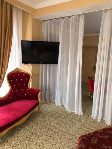 a hotel room with a red couch and a flat screen tv at Le Sart Resort in Vnukovo