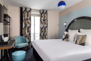 a bedroom with a bed and a desk and a chair at Hôtel Regina Opéra Grands Boulevards in Paris