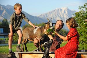 a man and two children feeding a goat at Der Stern - Nachhaltiges Wirtshaus und Landhotel seit 1509 in Obsteig