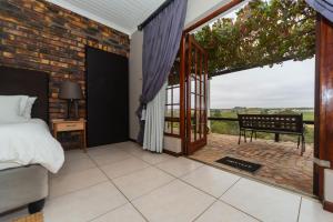 a bedroom with a bed and a balcony with a view at Melkboomsdrift Guest House & Conference Centre in Vredendal