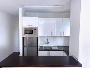 cocina con armarios blancos y nevera de acero inoxidable en Apartamento Playa de las Américas II, en Playa de las Américas