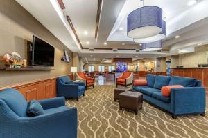 Comfort Suites Near Texas A&M - Corpus Christi في كوربوس كريستي: غرفة انتظار مع الأرائك الزرقاء وتلفزيون بشاشة مسطحة