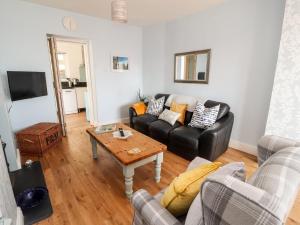 a living room with a black couch and a table at Euryn View in Llandudno