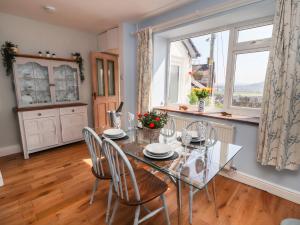 a dining room with a glass table and chairs and a window at Euryn View in Llandudno