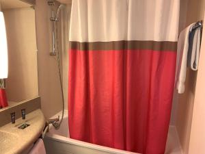 einem roten Duschvorhang im Bad neben einem Waschbecken in der Unterkunft Novotel Poissy Orgeval in Orgeval