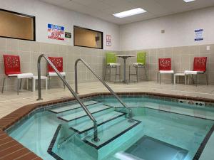 una piscina con sillas y mesas en un edificio en Comfort Inn Saint Paul East, en Oakdale