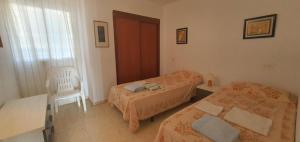 a bedroom with two beds and a white chair at COBLANCA 20 - Fincas Arena in Benidorm