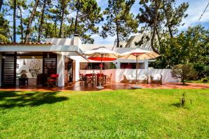 a house with two umbrellas and a yard at Cerca do Altinho in Vila Nova de Milfontes