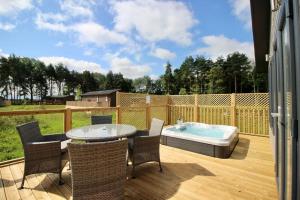 eine Terrasse mit einem Tisch und einer Badewanne auf einer Terrasse in der Unterkunft Hollicarrs - Bumblebee Lodge in York