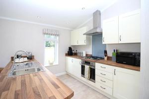 a kitchen with white cabinets and a sink at Hollicarrs - Bumblebee Lodge in York