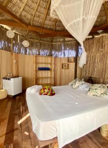 um quarto com uma grande cama branca com flores em Cabanadu Preá Kite em Praia do Preá