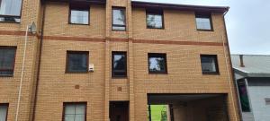 - un bâtiment en briques avec des fenêtres sur le côté dans l'établissement Espedair Apartment, à Paisley