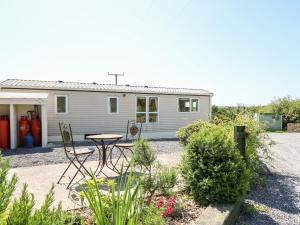 uma casa com uma mesa e cadeiras em frente em The Lodge em Llanelli