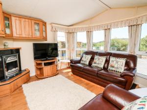 a living room with a leather couch and a television at The Lodge in Llanelli