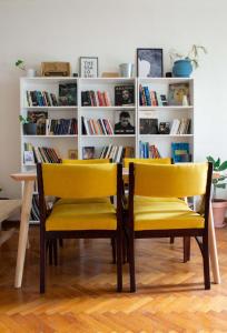 テッサロニキにあるAristotelous Square Apartmentの黄色い椅子と本棚のあるダイニングルーム