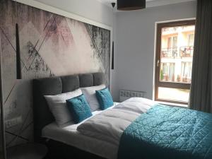 a bedroom with a bed with blue pillows at APARTAMENT D-7 W OBIEKCIE NAUTIKKA PARK in Krynica Morska