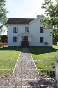 a white house with a gate in front of it at Jaktlyckan, Tuna Gård in Tuna