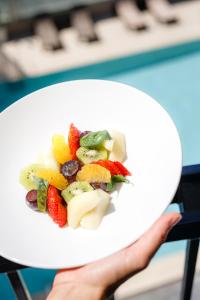 una persona sosteniendo un plato con fruta. en Hotel Helios Lloret, en Lloret de Mar