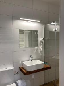 ein weißes Bad mit einem Waschbecken und einer Dusche in der Unterkunft Hostel Karpacki Szymon Szczepan in Zarszyn