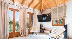 ein Wohnzimmer mit 2 weißen Stühlen und einem TV in der Unterkunft Ca's Pastor - Chalet de montaña in Escorca