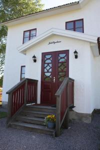 a white house with a red door and stairs at Jaktlyckan, Tuna Gård in Tuna