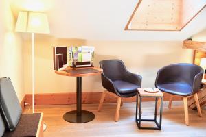 Cette chambre dispose de 2 chaises, d'une table et d'une télévision. dans l'établissement The Alpina Mountain Resort, à Tschiertschen